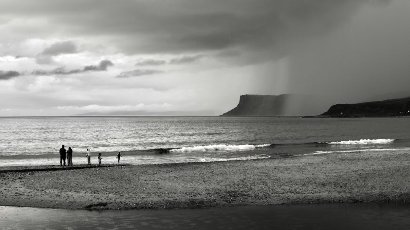 Paddling before the storm Family on sea shore as storm approaches , by Denis Taylor